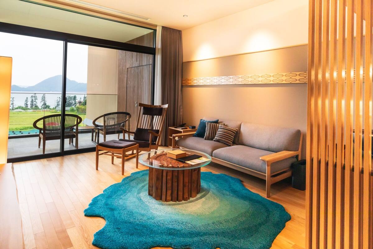 Una sala de estar moderna con un sofá, sillas, una mesa de centro y vistas a un lago.