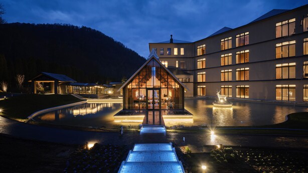 Ein modernes Hotel mit Glasfassade, Innenhof und Bergblick.