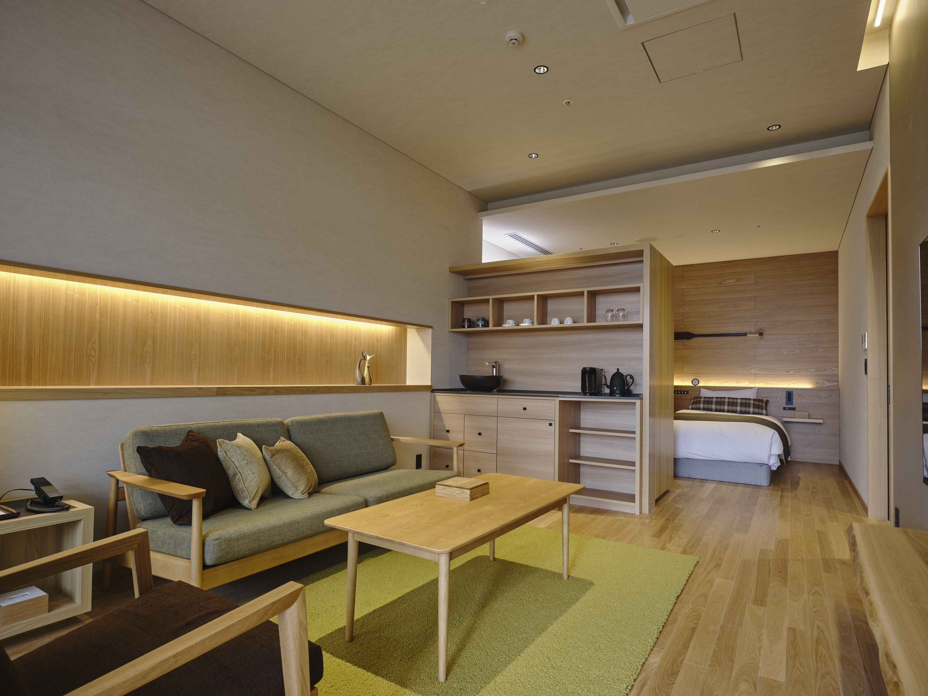 A modern, compact living space with a sofa, coffee table, and a kitchenette area.