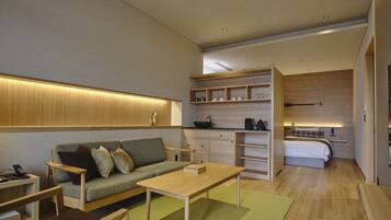A modern, compact living space with a sofa, coffee table, and a kitchenette area.