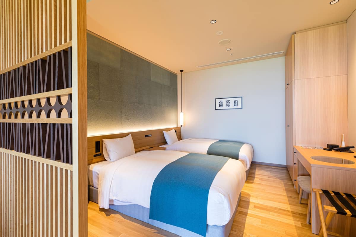 Una habitación de hotel moderna con dos camas, un escritorio y un armario empotrado.