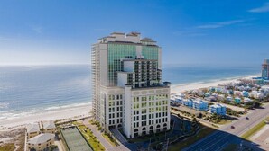 A high-rise hotel with a modern design, located near a beach with a clear view of the ocean. - The Oasis 610 | Spacious, Lazy River, Poolside Grill, New Splash Pad, Pool with Slide! (Orange Beach)