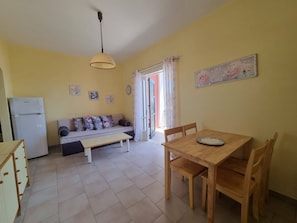 A compact living space with a kitchenette, a sofa, a dining table, and a ceiling fan.