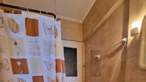 A bathroom with a shower curtain featuring a floral pattern, a toilet, a sink, and a window with a view of the outside.