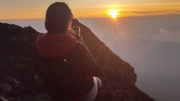 A person sitting on a rocky outcrop overlooking a vast landscape during sunset. - a very interesting tour held on top of Mount Batur, 4wd jeeps tour (Bali)
