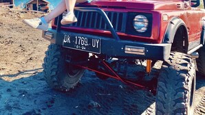 A person sitting on a red off-road vehicle with a visible license plate. - a very interesting tour held on top of Mount Batur, 4wd jeeps tour (Bali)