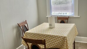 A dining area with a table set for two, featuring a checkered tablecloth and wicker chairs. - Historical Spacious 1-Bedroom Apartment Unit 3 (Shreveport)