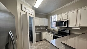 A kitchen with white cabinets, stainless steel appliances, and a sign reading "Laundry Room". - Safe, Central, Cozy Home with Private Parking, KING Bed, near DFW Airport & more (Euless)