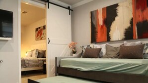 Un dormitorio moderno con una cama grande, un televisor montado en la pared y un cuadro sobre la cama.