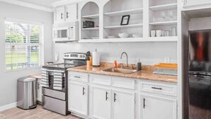 Una cocina moderna con armarios blancos, horno de acero inoxidable, microondas y refrigerador.