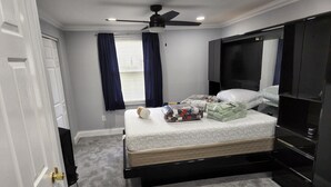 Une chambre à coucher avec un lit, un ventilateur de plafond, une télévision et une armoire.