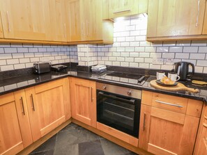 A kitchen with wooden cabinets, a black countertop, a stove, an oven, and a coffee maker.