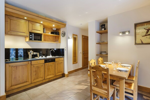 A kitchen with wooden cabinets, a microwave, and a dining area with a table set for two.