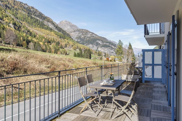Un balcone con tavolo e sedie, affacciato su un paesaggio montuoso.
