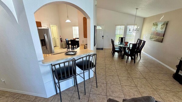 A kitchen with a dining area, featuring a counter, chairs, and a table.