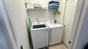 Un lavadero con dos lavadoras blancas, un tendedero con toallas dobladas y un paño de secado verde.