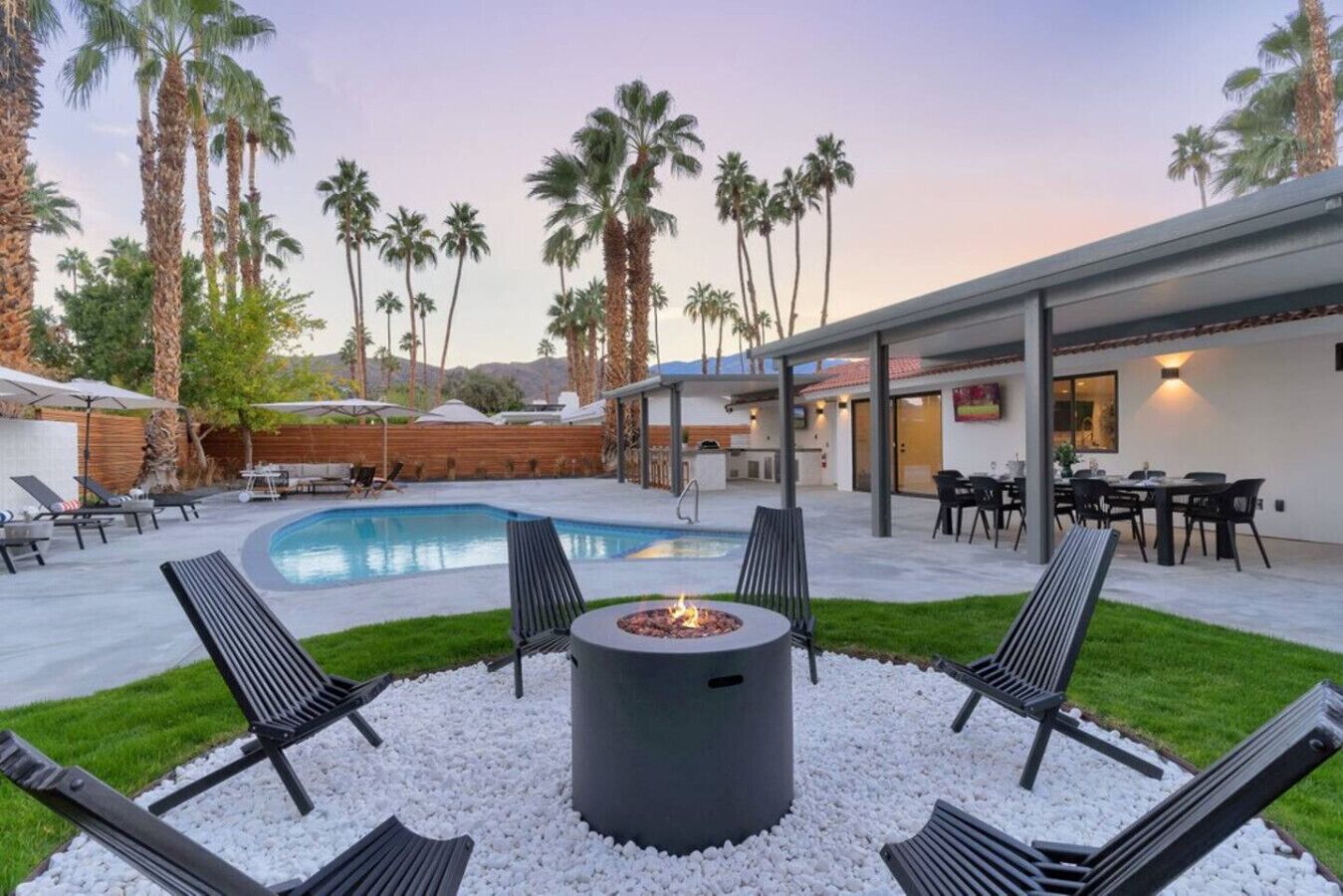A backyard with a swimming pool, a fire pit, and outdoor seating.