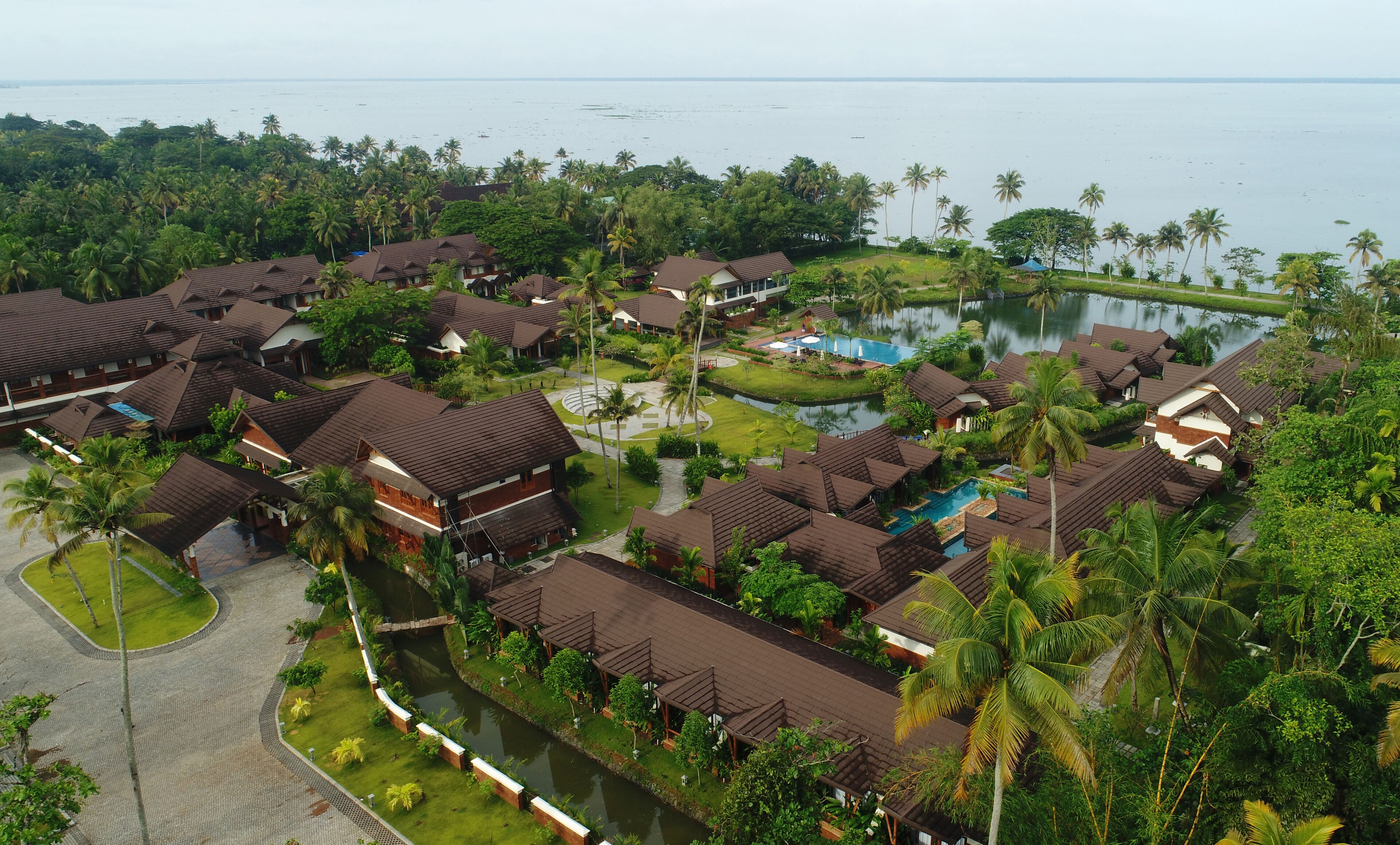A resort with multiple bungalow-style buildings, a swimming pool, and a surrounding lush landscape.