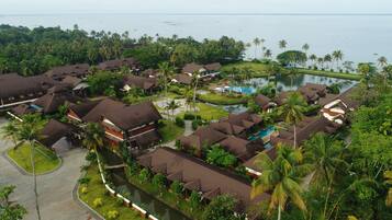 A resort with multiple bungalow-style buildings, a swimming pool, and a surrounding lush landscape.