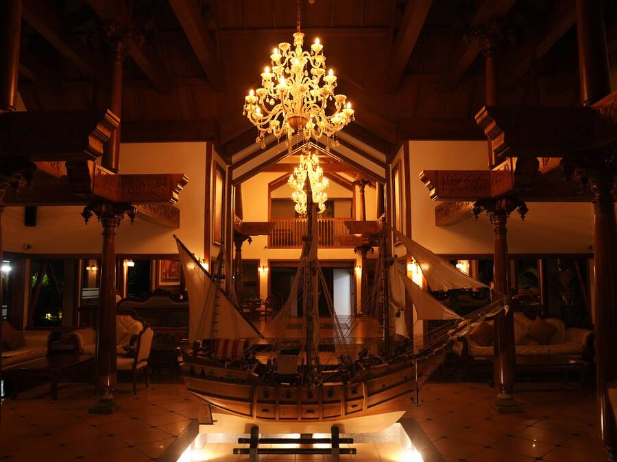 A grand hall with a large, ornate chandelier, a ship model, and classical architecture.