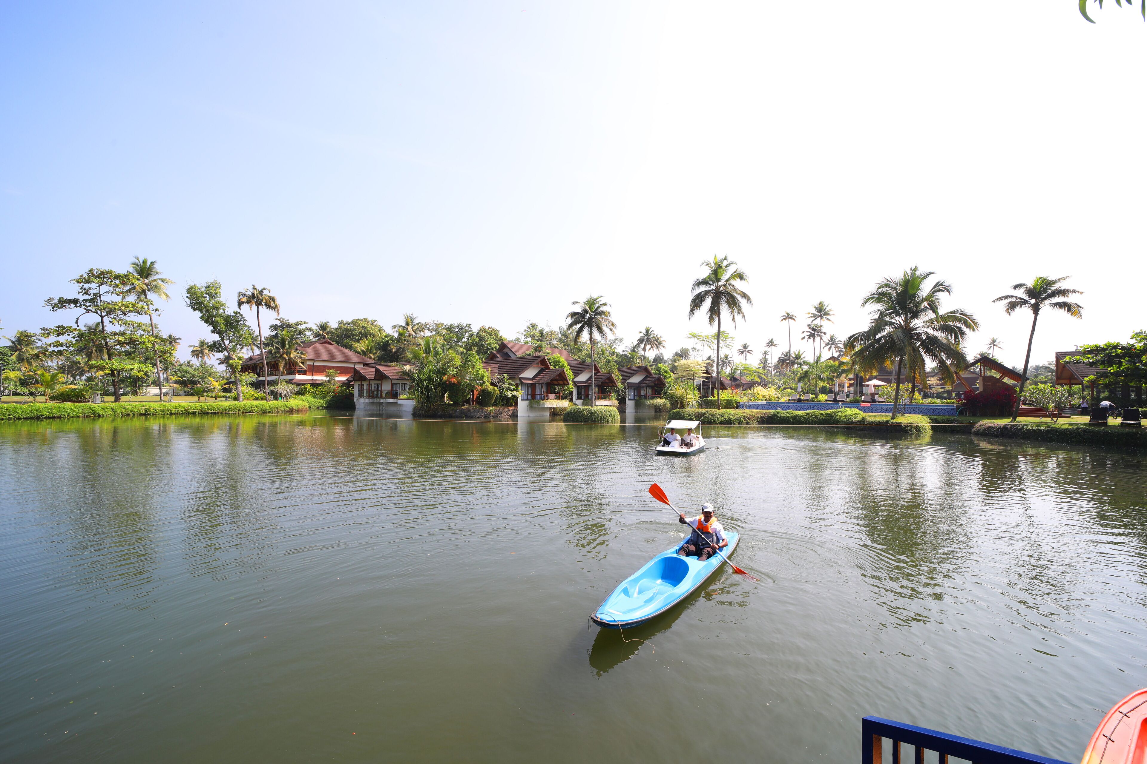 A calm lake with a kayak in the foreground and a boat in the background.