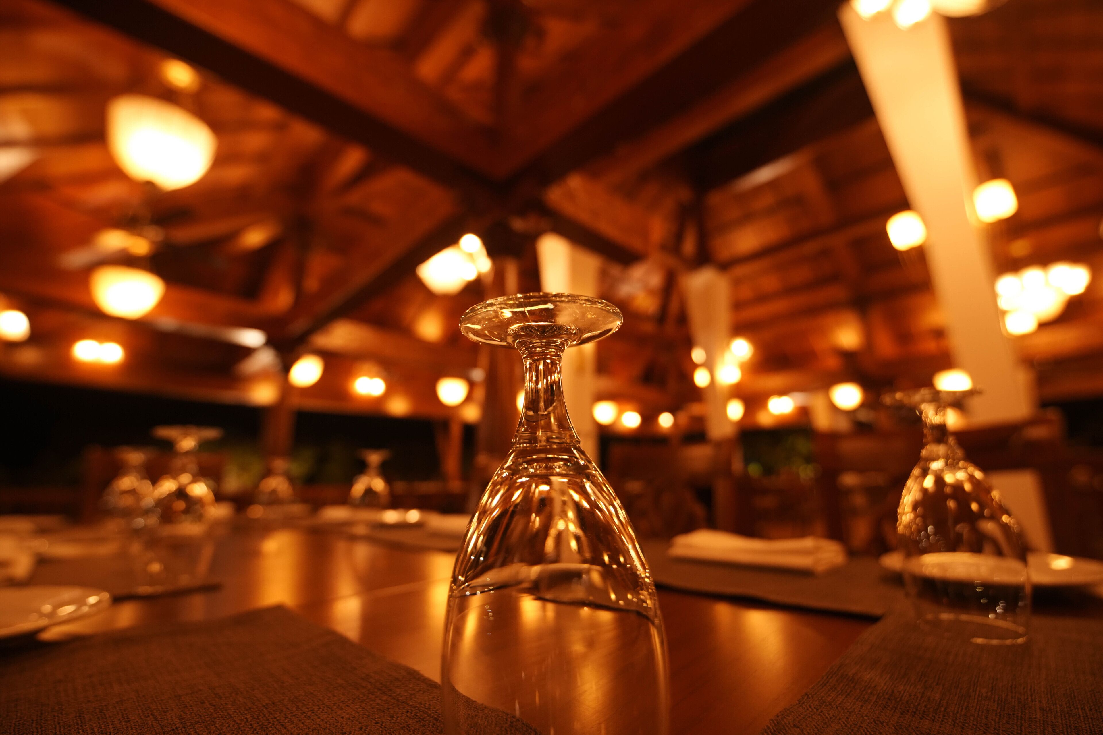 A dining table with a clear glass bottle in the foreground, surrounded by plates and cutlery.