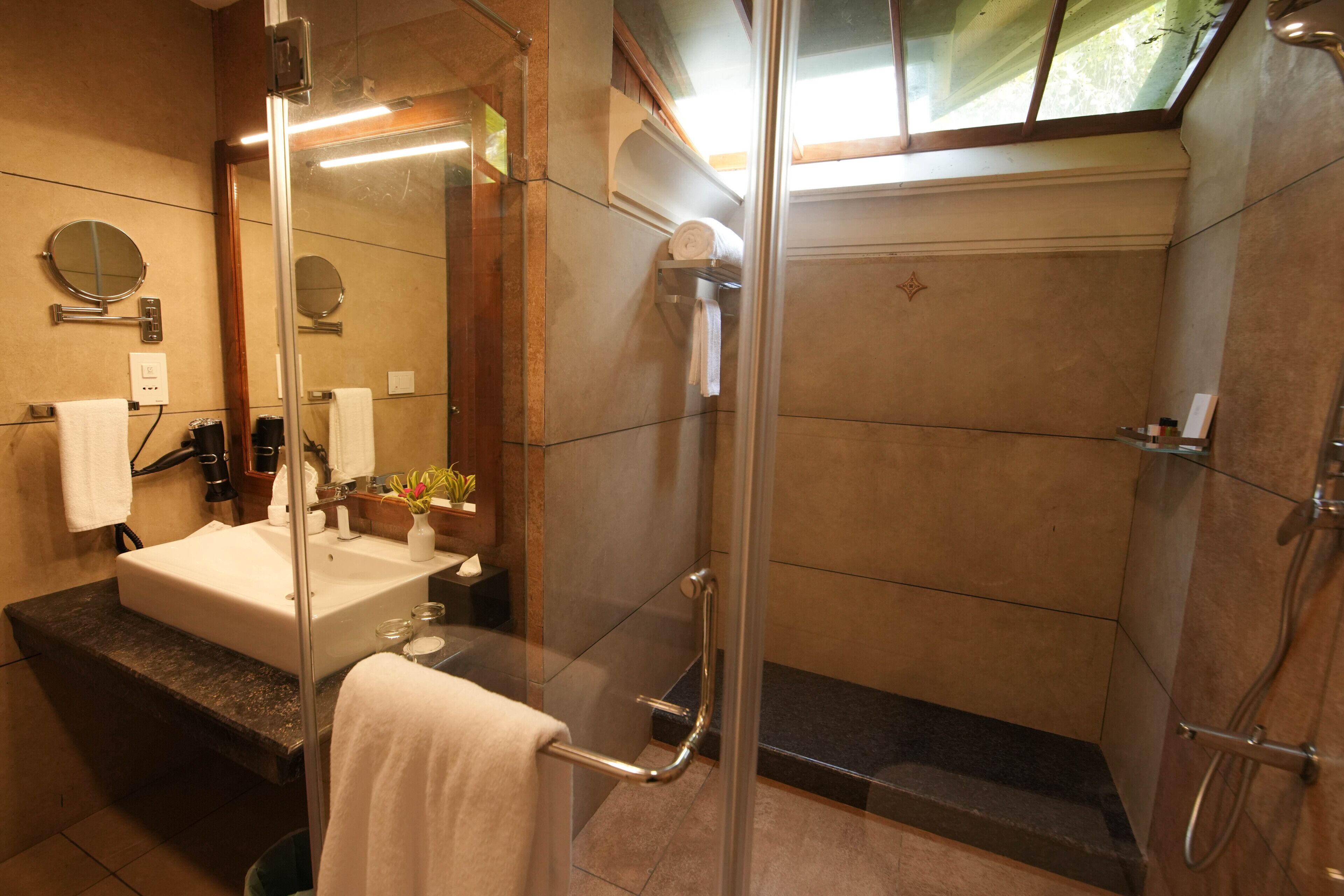 A modern bathroom with a glass-enclosed shower, a sink with a mirror, and a towel rack.