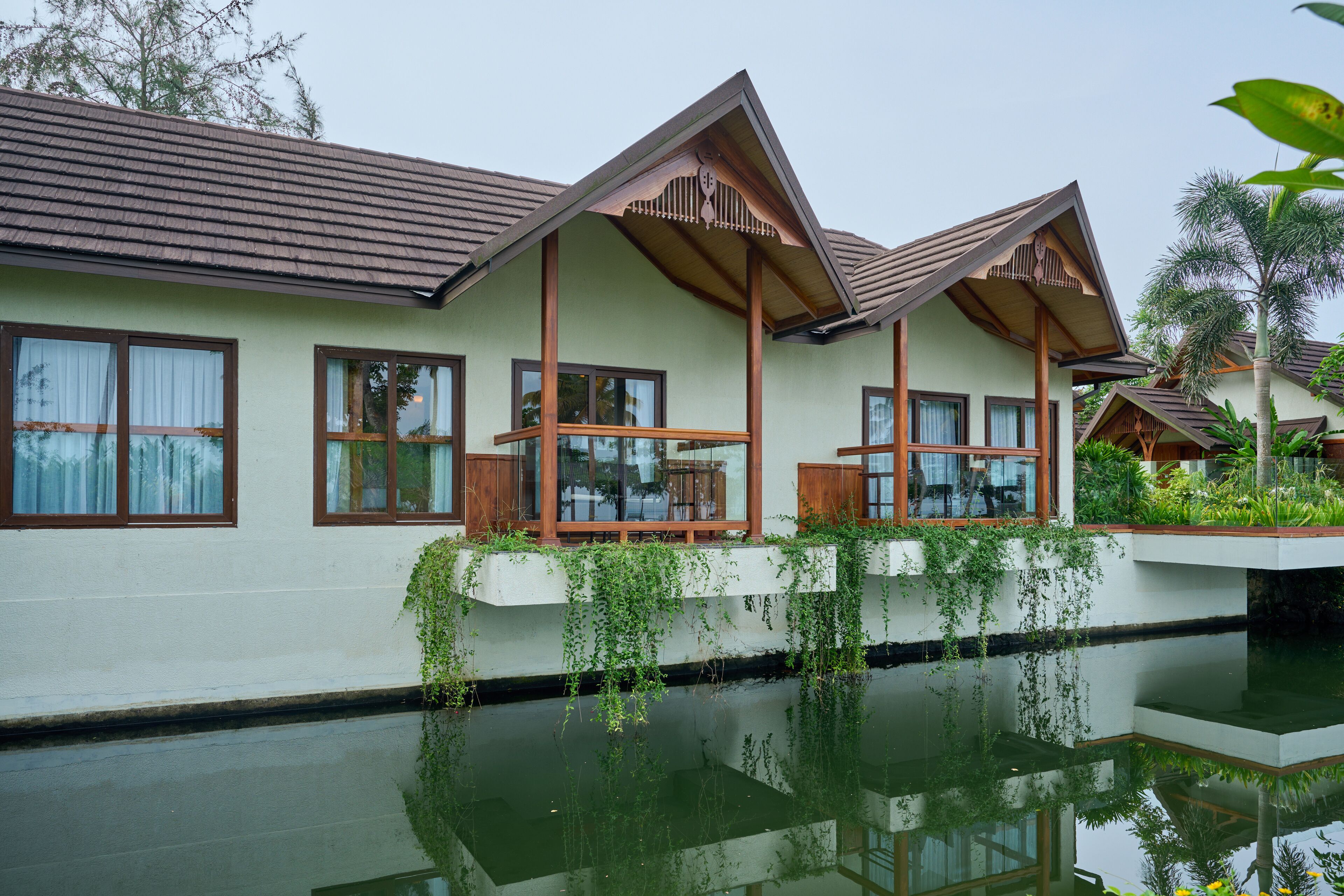 Een resort met een groot wateroppervlak ervoor, houten balkons en een lichtgekleurde gevel.