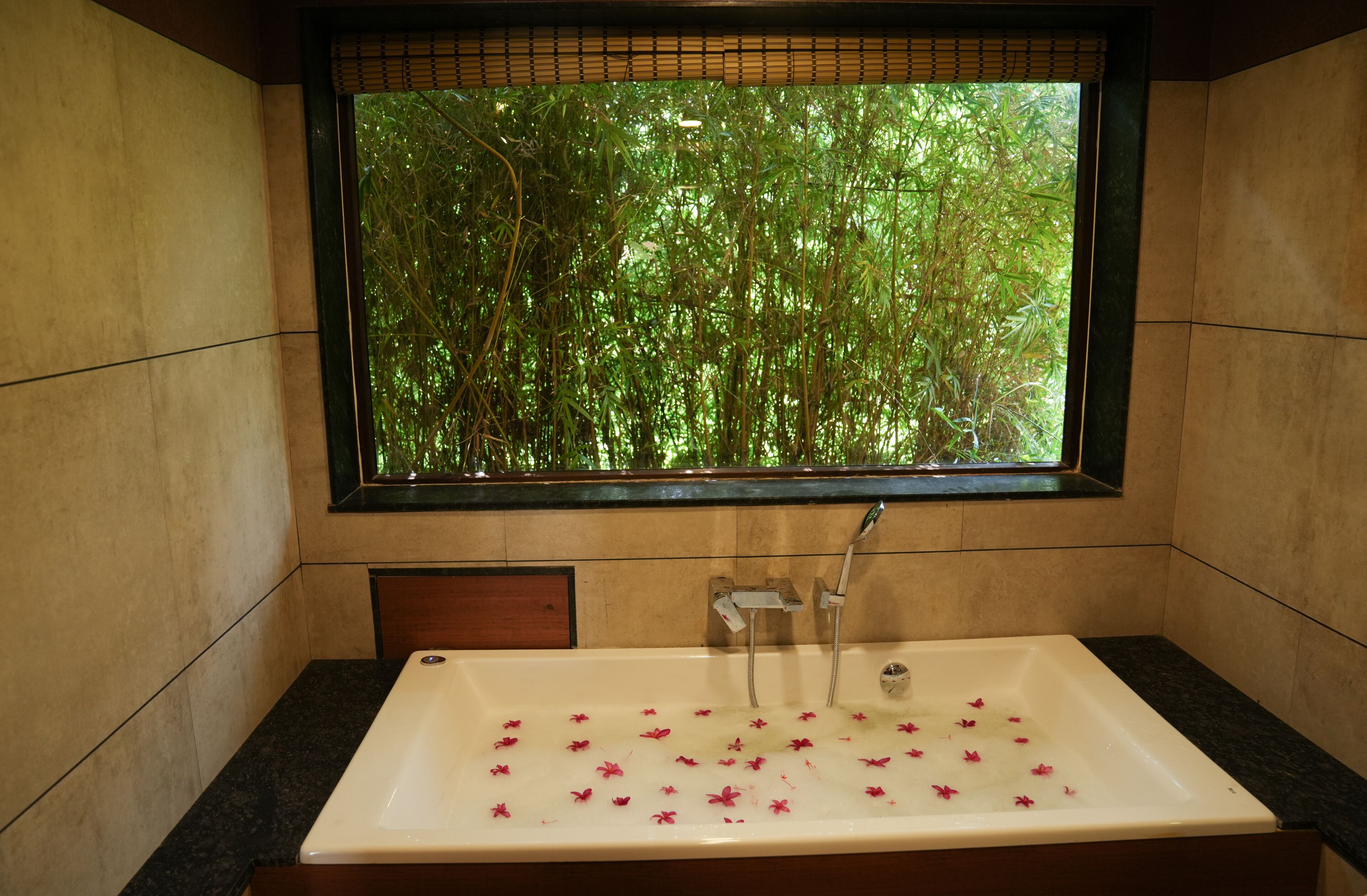 Un baño con un ventanal grande, una bañera y un banco de madera.
