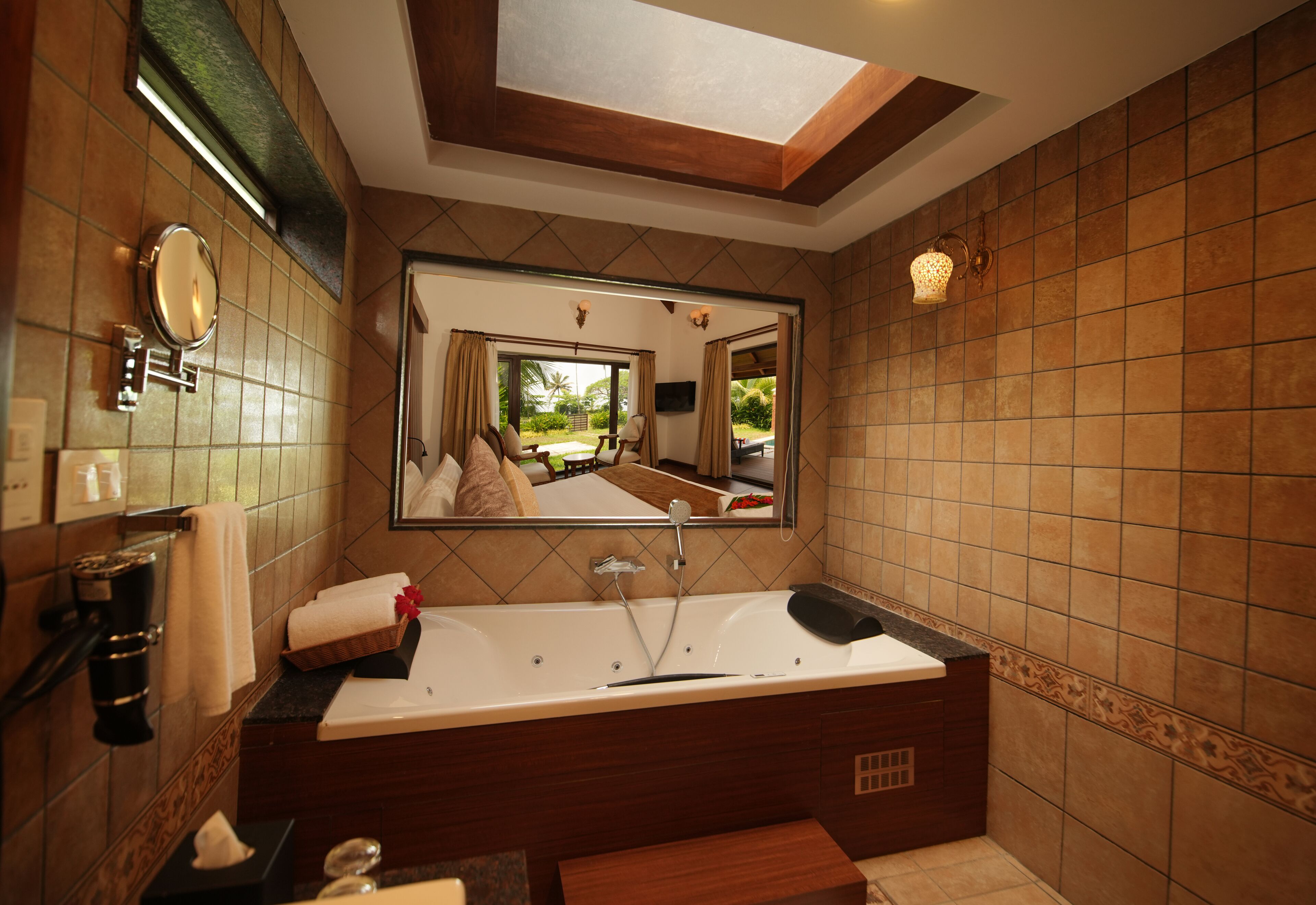A modern bathroom with a large bathtub, a mirror, and a skylight.