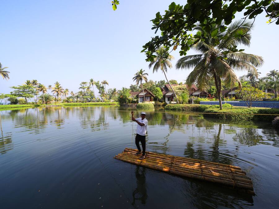 Una persona sobre una plataforma flotante en aguas tranquilas, rodeada de exuberante vegetación y palmeras.
