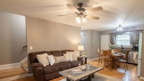 A living room with a brown sofa, a coffee table, and a ceiling fan.