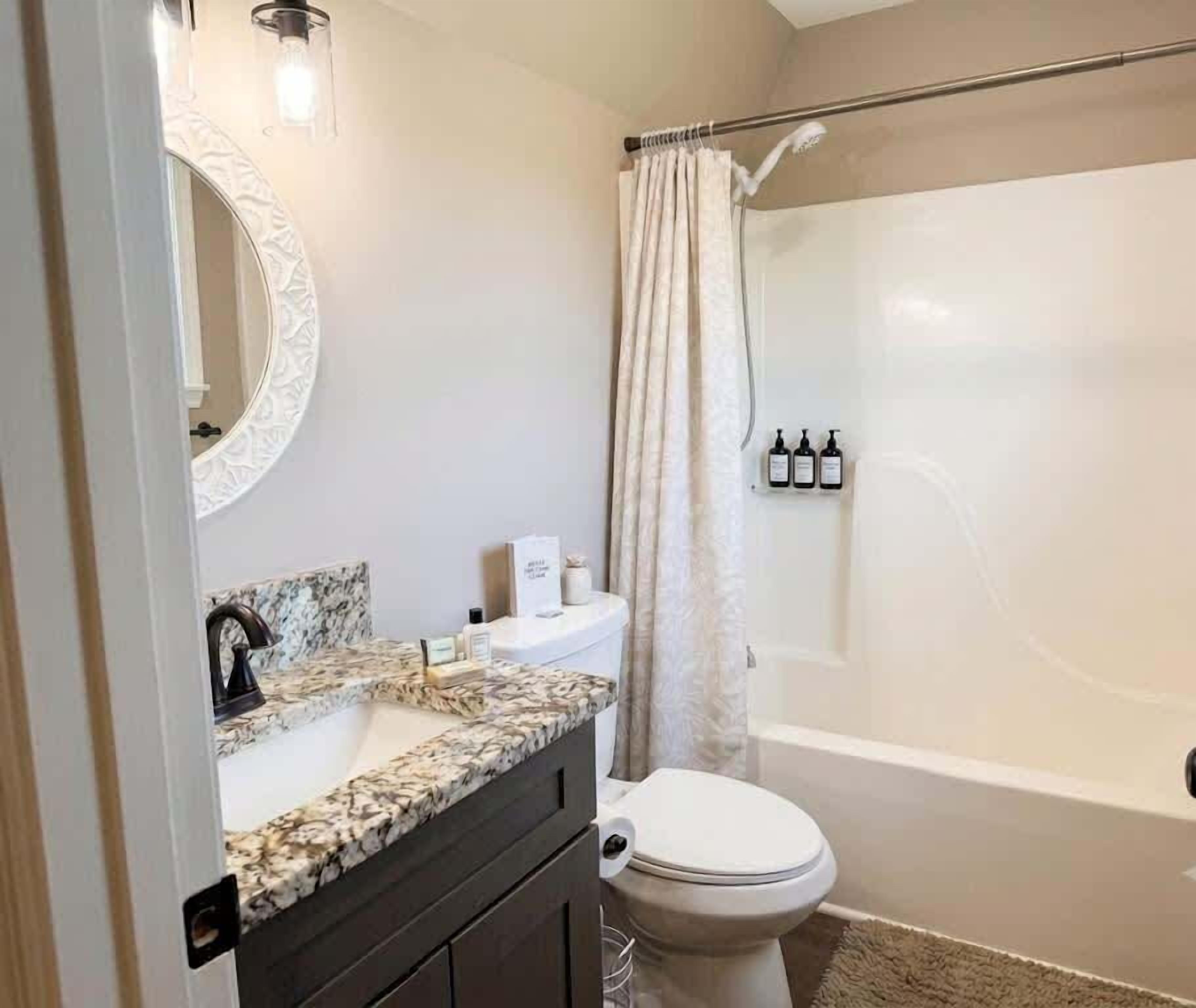Un baño con ducha, inodoro, lavabo y espejo.