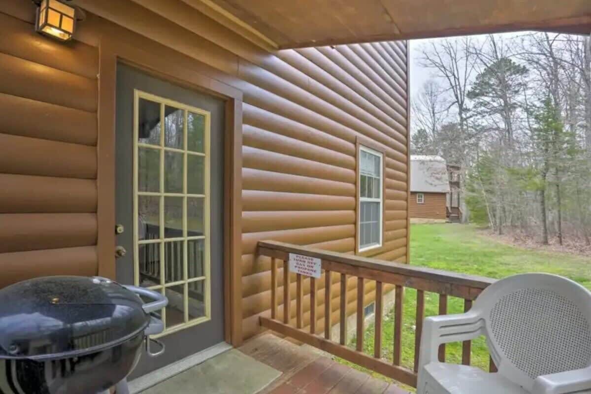 A log cabin with a porch, a grill, and a chair.