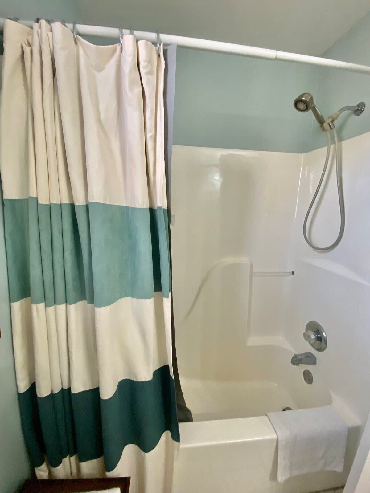 A bathroom with a bathtub, shower, and curtain.