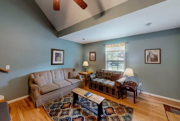 A living room with a beige sofa, a plaid sofa, a coffee table, and a patterned rug. - The Loose Moose with a private hot tub! (Rising Fawn)