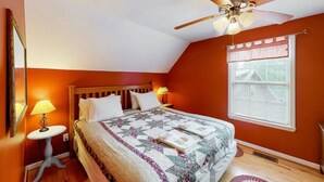 A bedroom with a wooden bed, a ceiling fan, a window with blinds, and a small table with a lamp. - The Loose Moose with a private hot tub! (Rising Fawn)