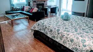 Een ruime woonkamer met een groot bed, een open haard, een bank en een salontafel.