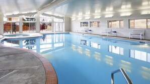 Ein Innenpool mit klarem Wasser, umgeben von weißen Wänden und großen Fenstern.