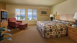 Ein Hotelzimmer mit einem großen Bett, einem Sessel, einem Fernseher und einem Fenster mit Blick auf die Berge.