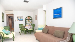 Un salon avec un canapé, des fauteuils, une table et une bibliothèque.