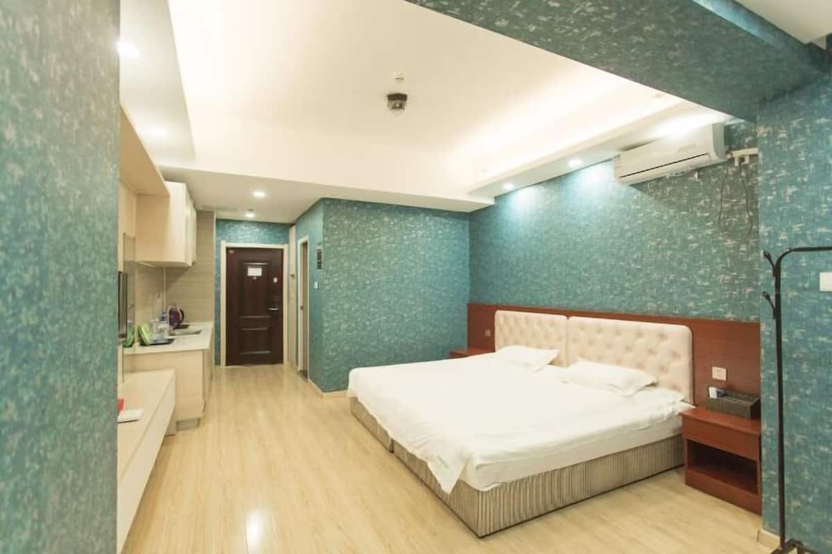 Un dormitorio con una cama grande, una mesita de noche, un armario y un baño con lavabo y espejo.