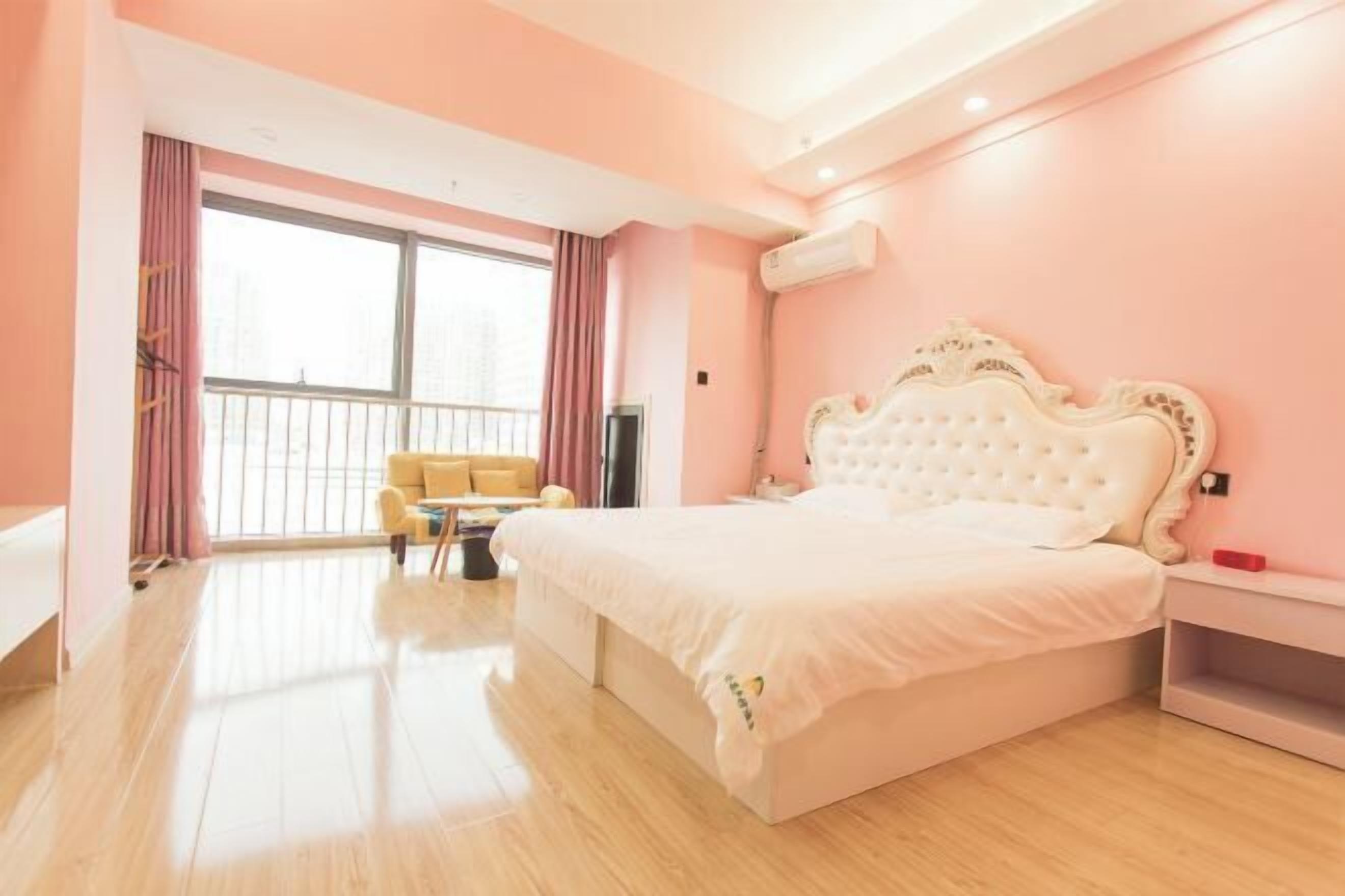 Un dormitorio con una cama grande, una mesita, una silla y una ventana con cortinas.