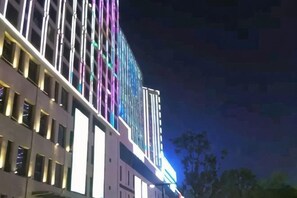 A multi-story building with a modern architectural design, featuring a series of windows and a facade with illuminated panels. - Mango Hotel (Bengbu)