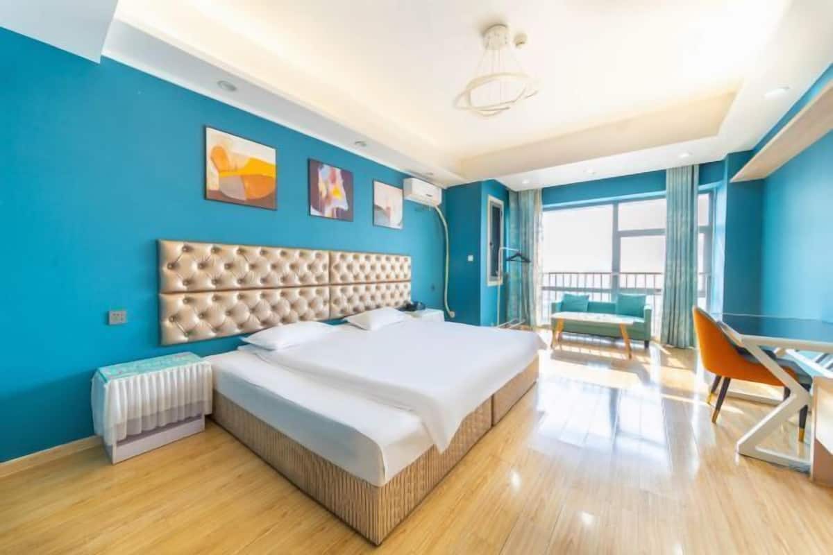Una habitación de hotel moderna con una cama grande, un escritorio y un balcón con vistas.