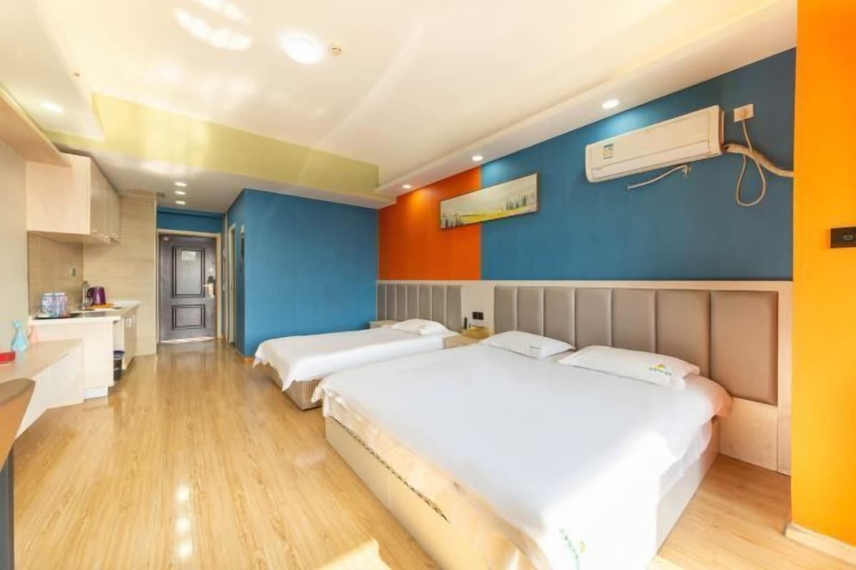 A hotel room with two beds, a kitchenette, and a bathroom.