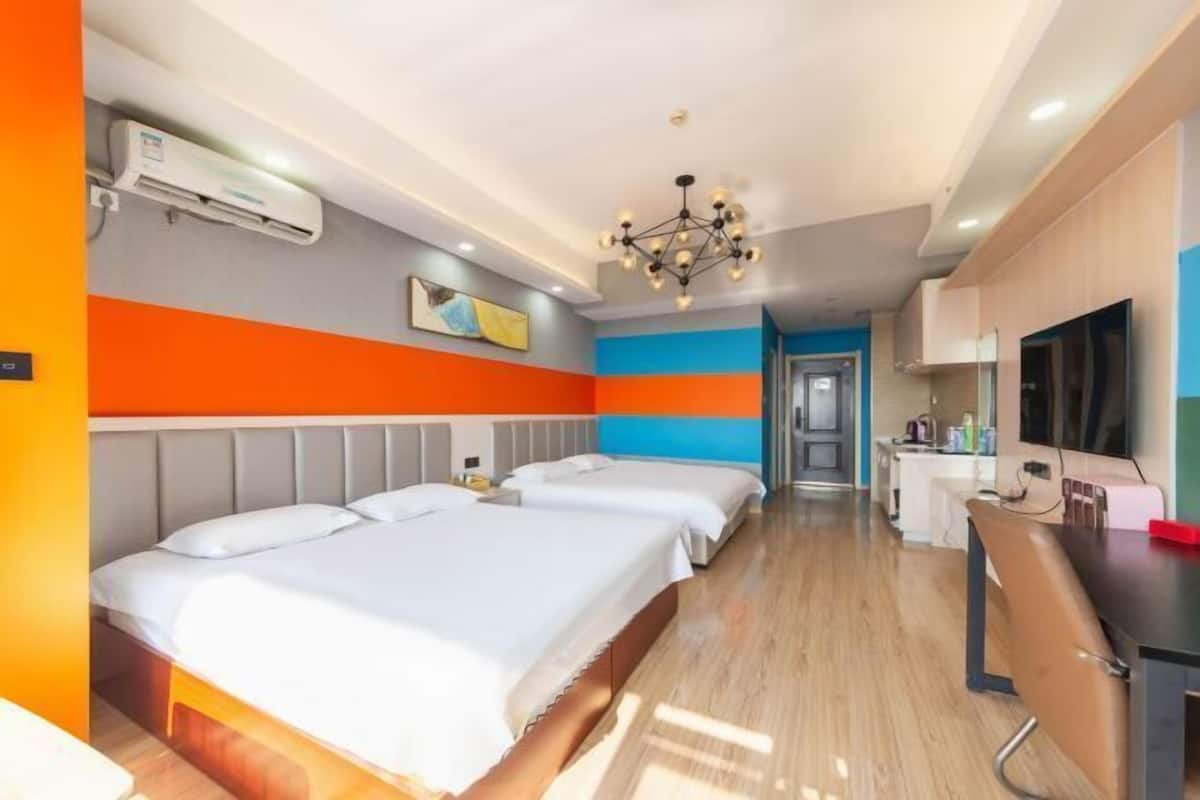 Una habitación de hotel con dos camas, un escritorio, televisión y kitchenette.