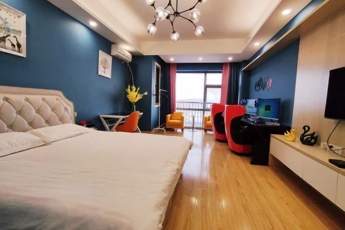 Habitación de hotel con una cama grande, un escritorio con computadora, una silla y un televisor.