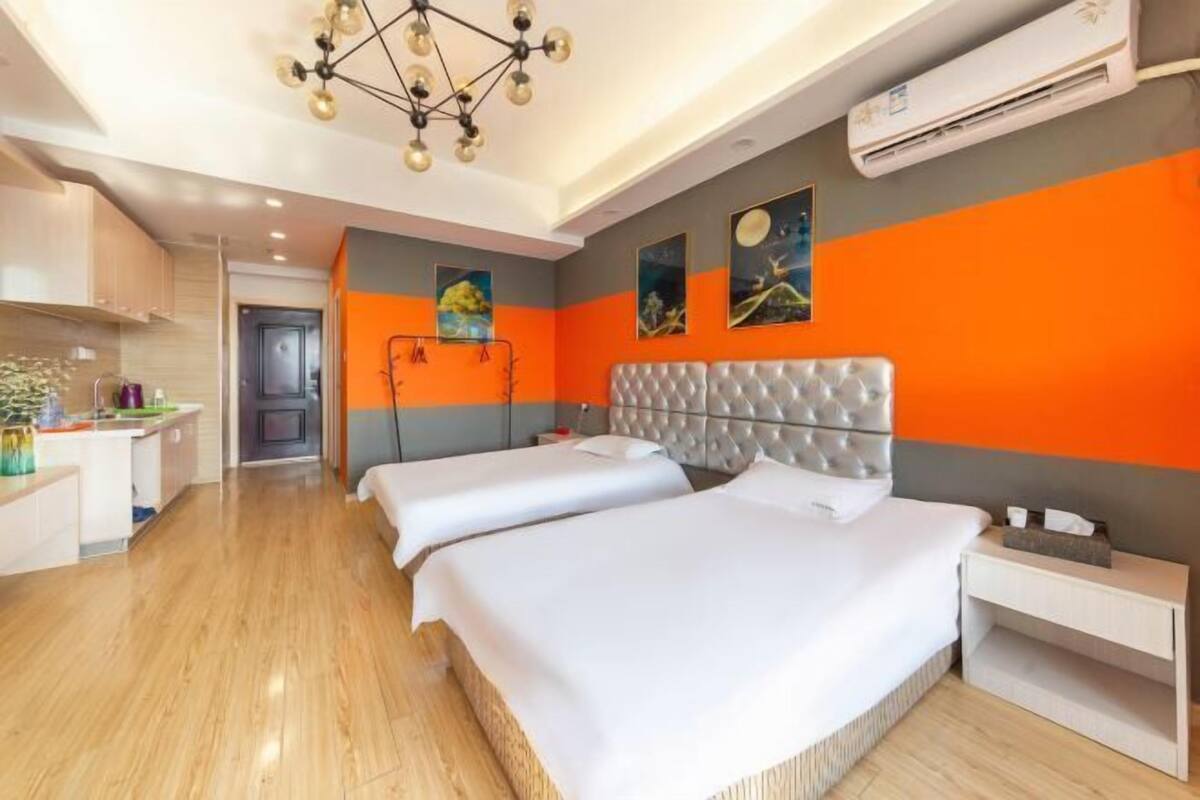 Una habitación de hotel con dos camas, una lámpara de araña moderna y obras de arte en las paredes.