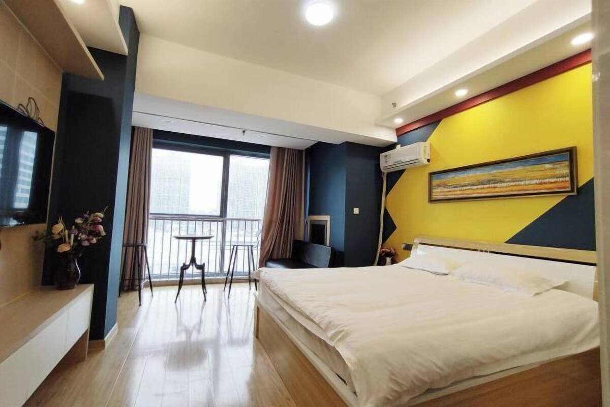 Una habitación de hotel con cama, televisor, balcón y un cuadro en la pared.